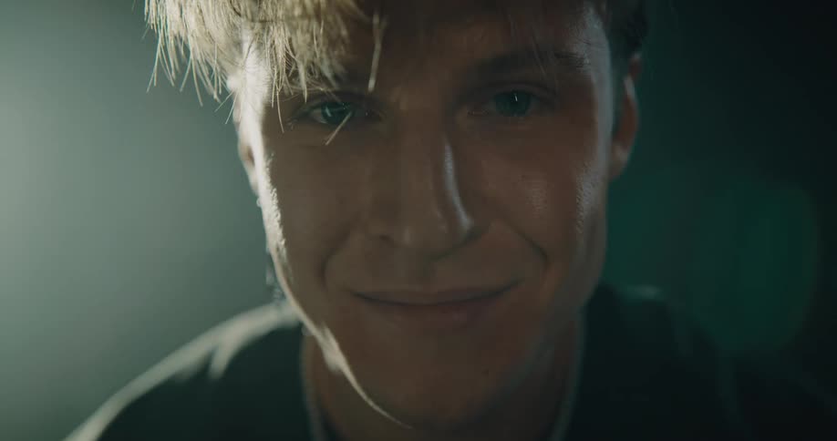 A man is looking down and he looks up and smiles