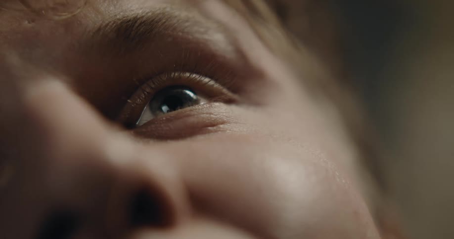 Ecu of young person right side of face and eye gazing scanning and eventually smiling reaction