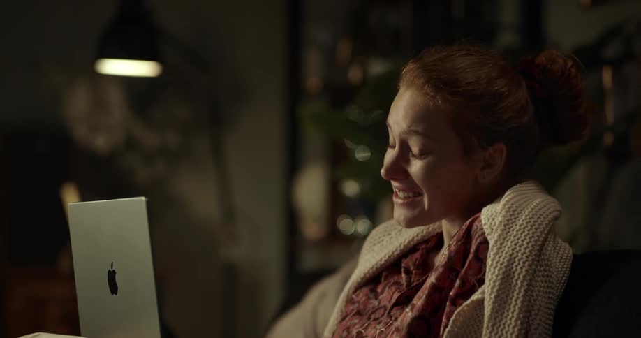 A woman with a smile on her face having a happy conversation on her laptop enjoying the moment and feeling content