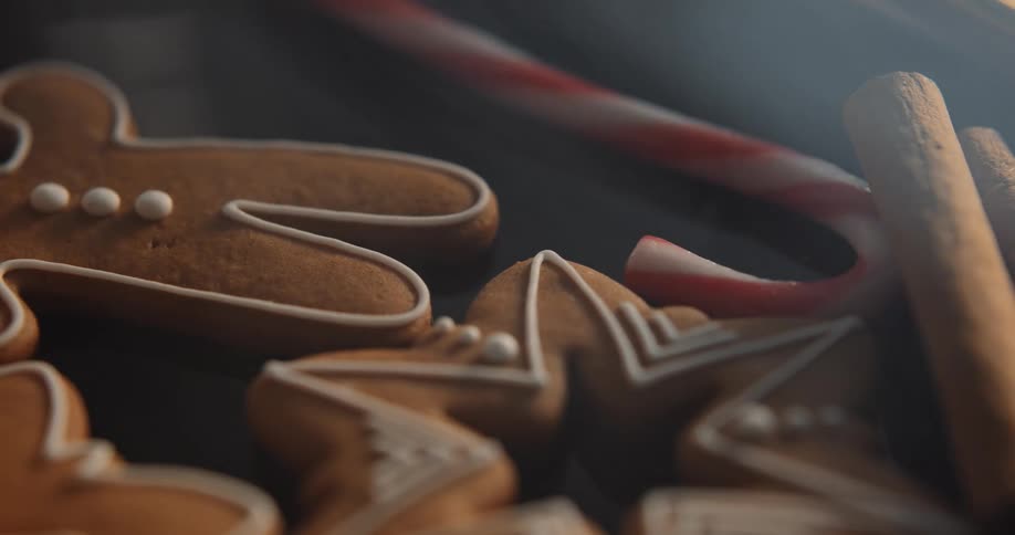 An close view of a plate of gingerbread cookies with cinnamon sticks and candy canes
