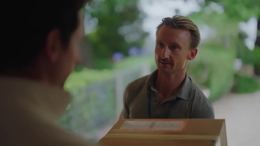 A delivery man giving a customer his package and giving him a paper for confirmation