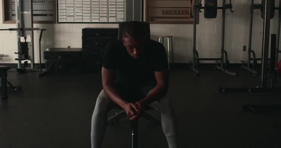 A man sits on a bench in a weight room