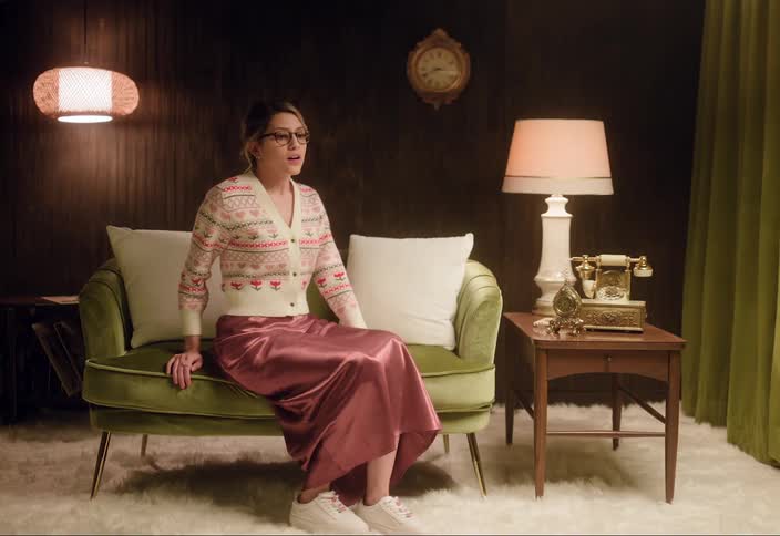 A woman is sitting on a couch and then gets up