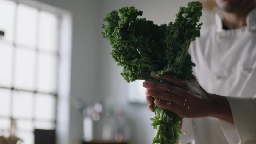 Person shaking water off of a bunch of kale