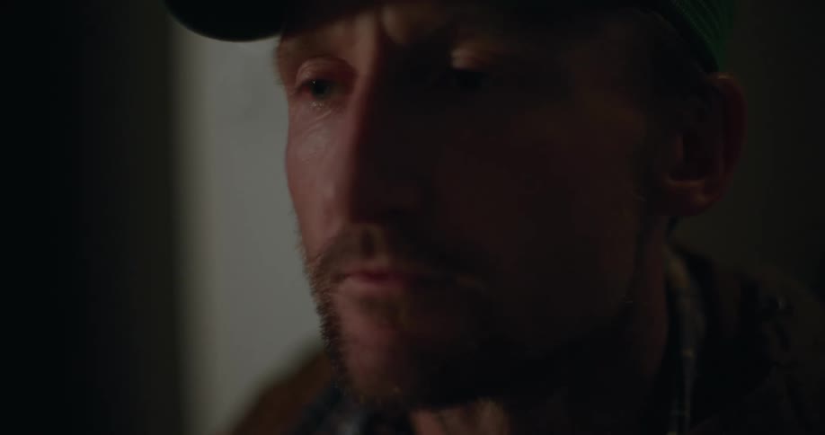 A closeup shot of a mans face as he sits and appears to be lost in thought with a look of sadness and despair