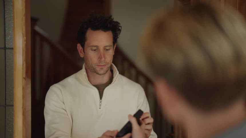 A man delivers a package to a home and has the man sign a tablet for it