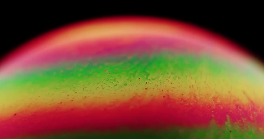 Streaks form as vivid layers of mixture swirl and move under in sphere against a dark background