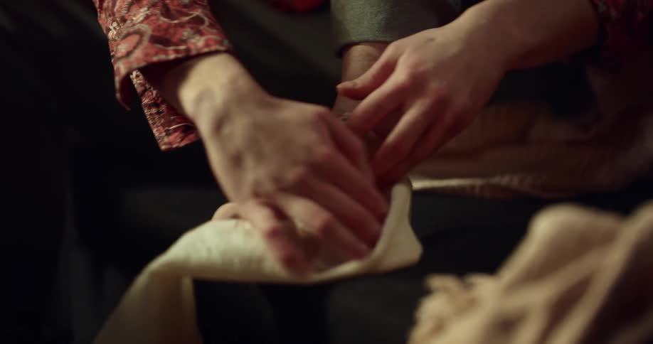 A woman is sitting with her foot up as she rubs ointment from a tube on her ankle and wraps it with a bandage