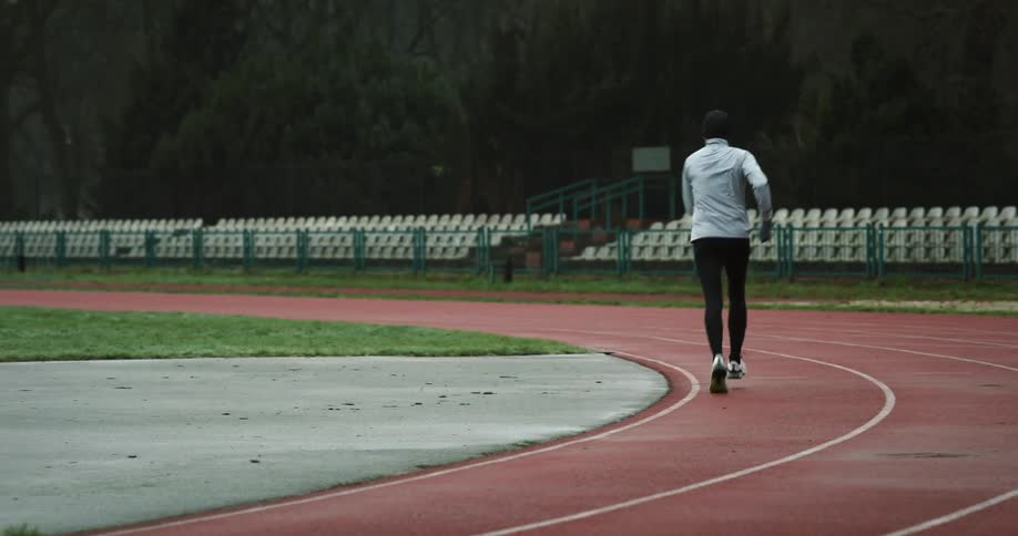 Two people run in opposite directions on running track