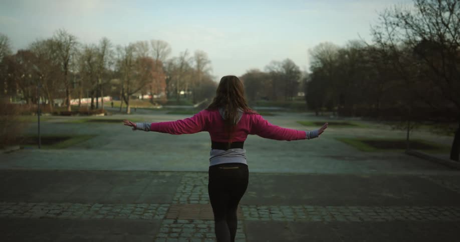 A woman is standing outdoors and dancing by herself