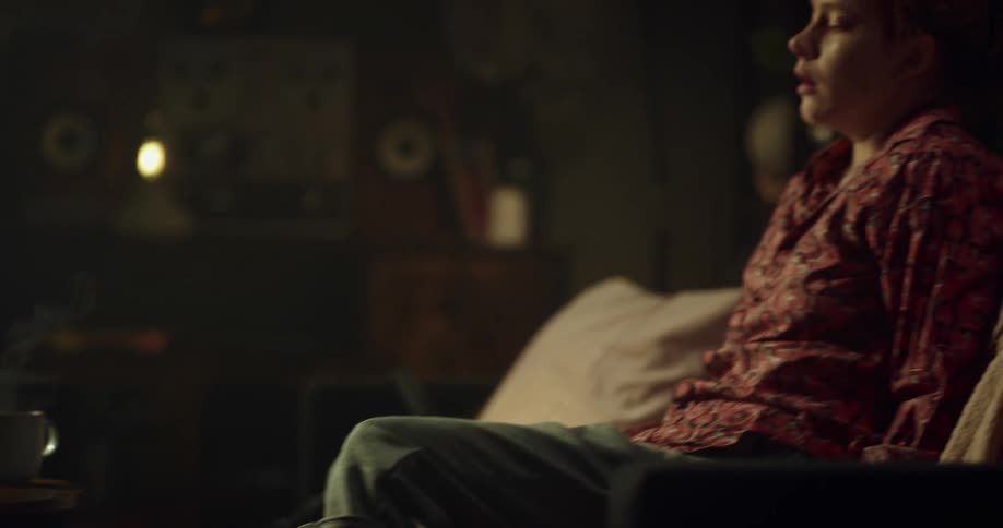 A woman is walking and sits on a couch indoors
