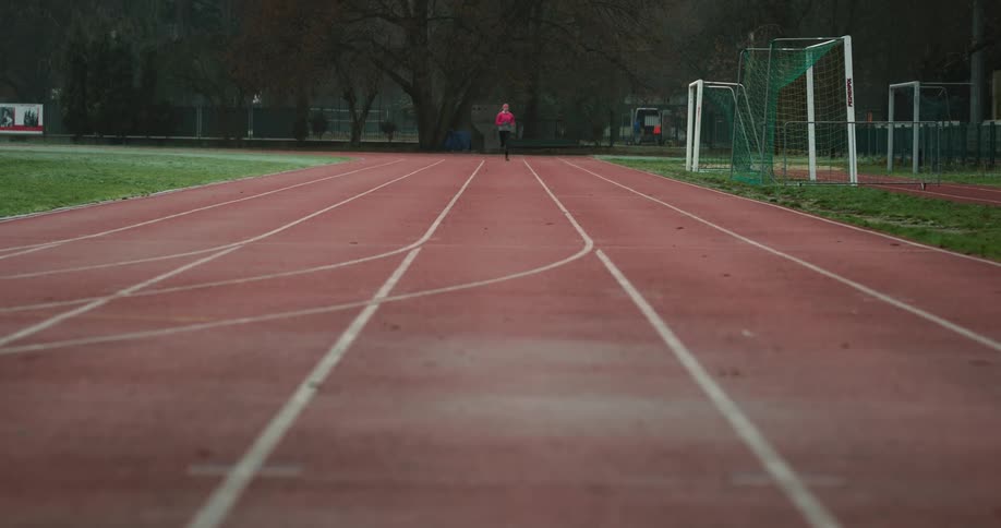 A woman runs down a track in a stadium