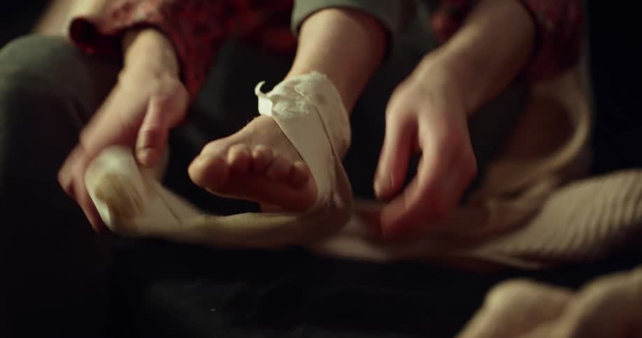 Woman removes a compression wrap and applies lotion on her ankle