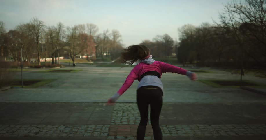 A woman is dancing by herself on tarmac