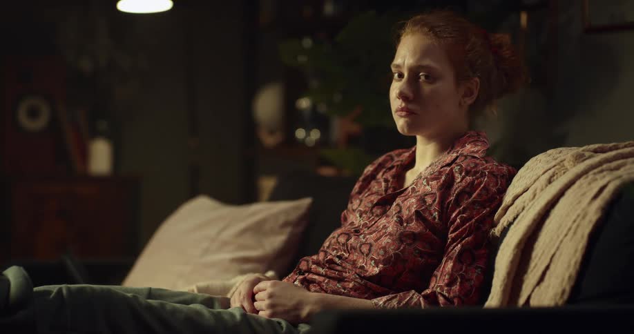 Woman sits on couch with teary eyes