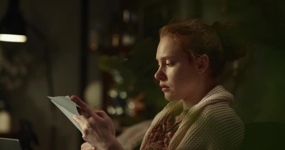 A woman is sitting on a couch and reading