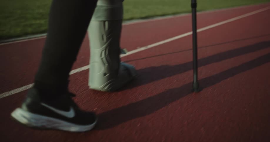 Woman walking on a track and field like using crutches