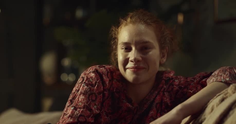 Redhead sitting on couch turns to smile