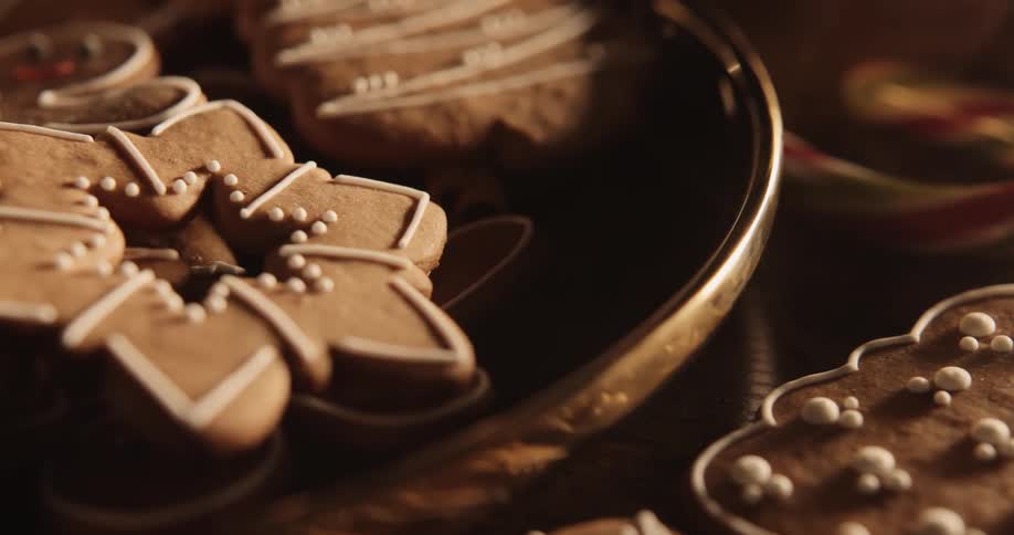 Holiday cookies are on a plate and on the table with a candy cane as a wisp of smoke floats over the table
