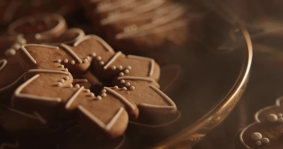 A smiling gingerbread man is on a tray with other holiday cookies as smoke moves across the table