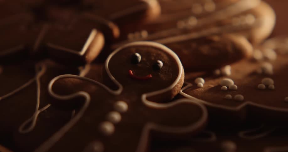 A smiling gingerbread man looks up from a plate of holiday gingerbread cookies