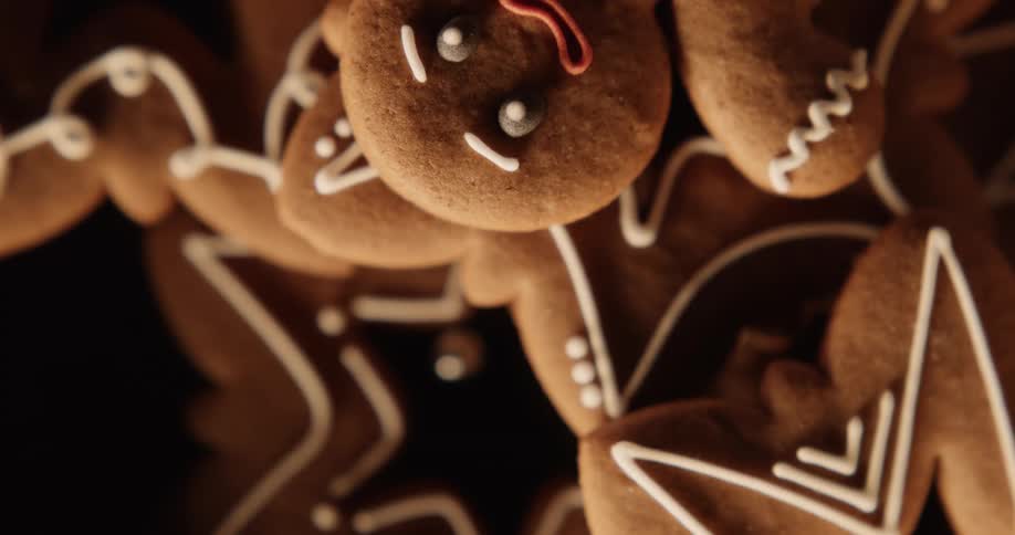 Holiday cookies are stacked on a plate as flickering light shines on them