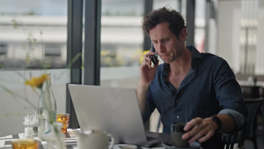 A man drinking juice while using a computer