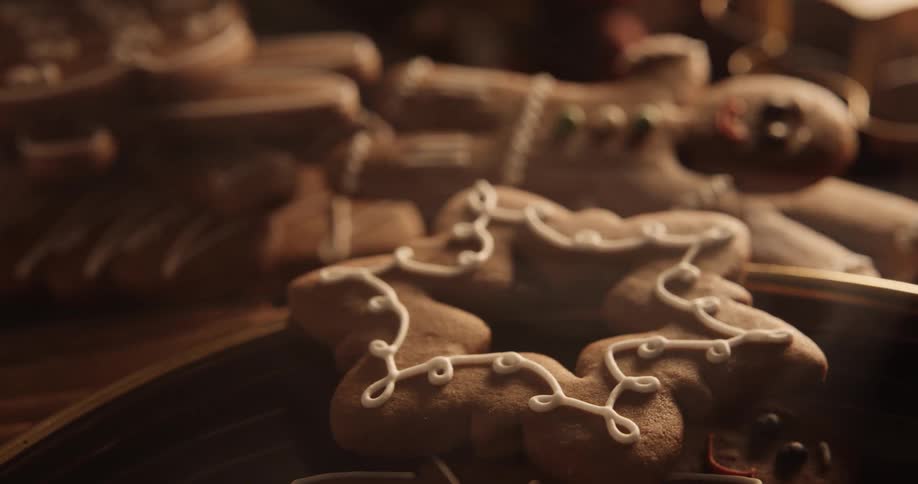 A smiling gingerbread man is on top of a cookie pile looking over at cookies on a plate as smoke moves across the table