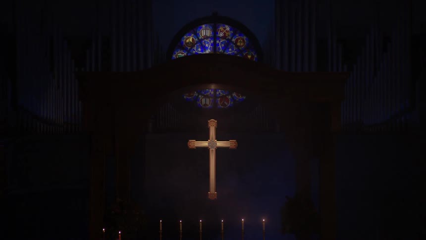 An illuminated cross hangs in a dark church
