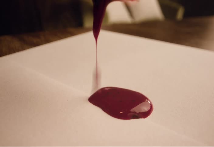 Closeup red wax being dripped onto the back of an envelope in preparation to be sealed with a stamp
