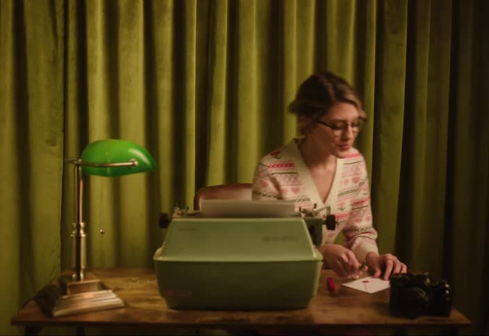 Female secretary sitting at desk with manual typewriter stands with a smile