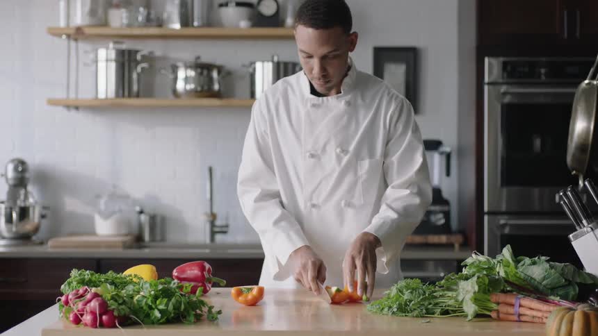 A chef slicing orange bell peppers