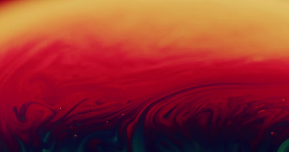 Red and yellow blend into an orange mixture as it swirls and blends with green as it moves across the surface