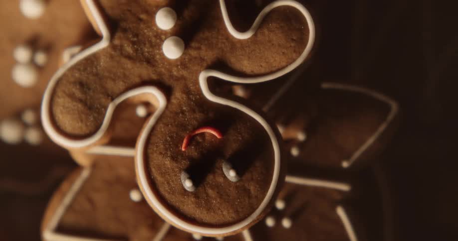 A smiling gingerbread man looks up from the top of a pile of cookies