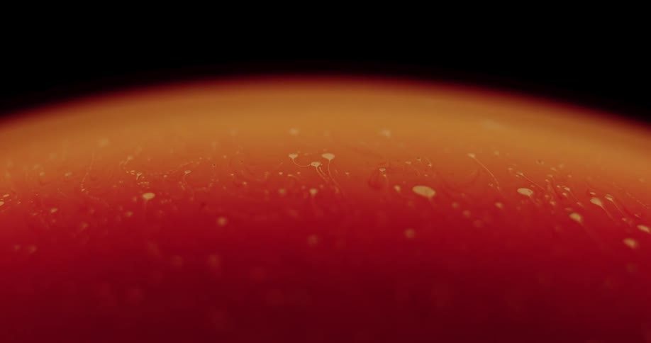 Yellow and orange objects move across a yellow globe and as they leave the surface the globe changes colors and becomes deep red with an orange hue