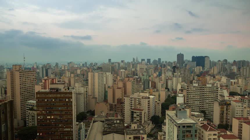 Clouds pass over a metropolis as the sky grows dark