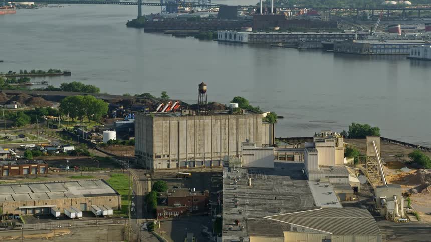 Aerial footage of a factory building located alongside the Delaware River in Camden NJ during a partly cloudy day in the summer