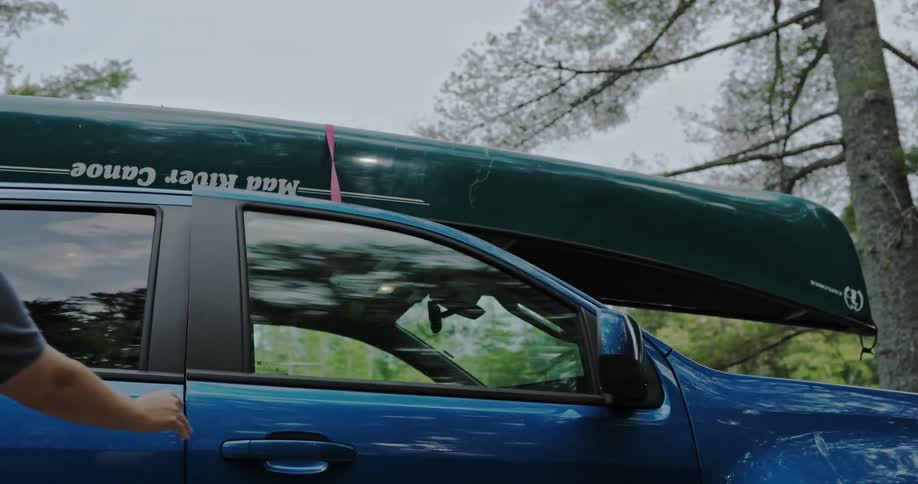 Woman closes door of car with canoe tied to its roof