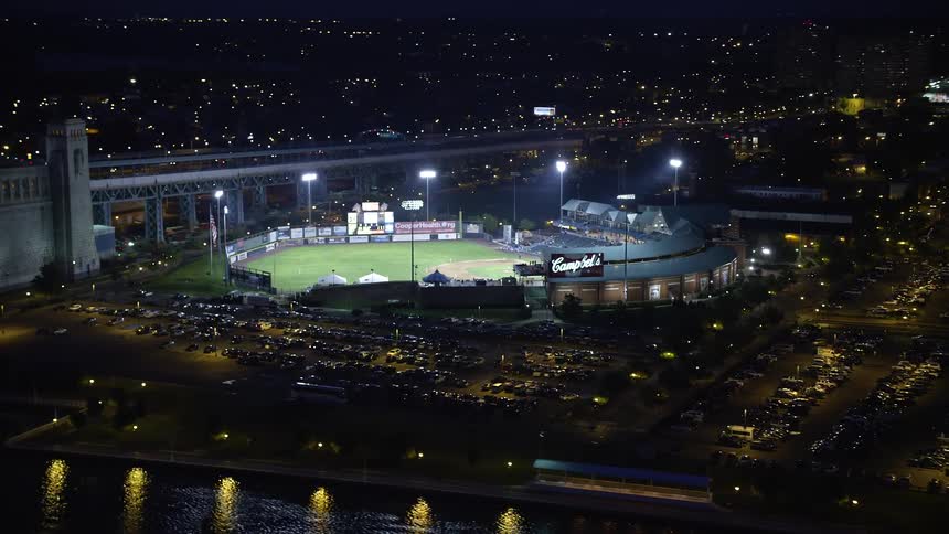 Aerial view of illuminated city buildings and baseball stadium