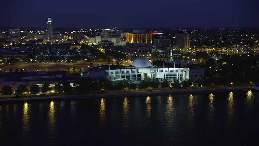 A nighttime aerial view of Adventure Aquarium by the Delaware River in Camden New Jersey showcasing the clear skies and reflection of lights on the water