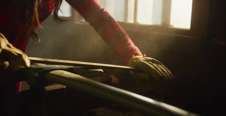Woman sharpens ax on workbench using metal rasp