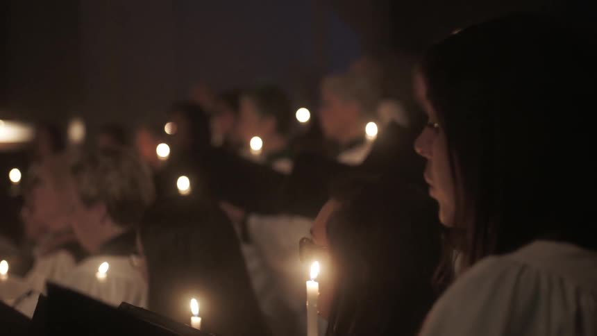 A church choir sings while holding candles