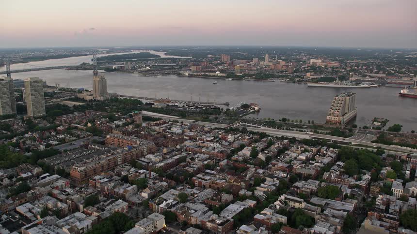 An aerial drone approaches the Delaware River and Camden New Jersey during sunset over South Philly