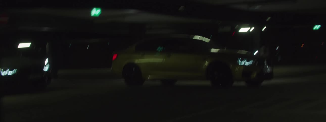 Two cars drive through parking garage at night
