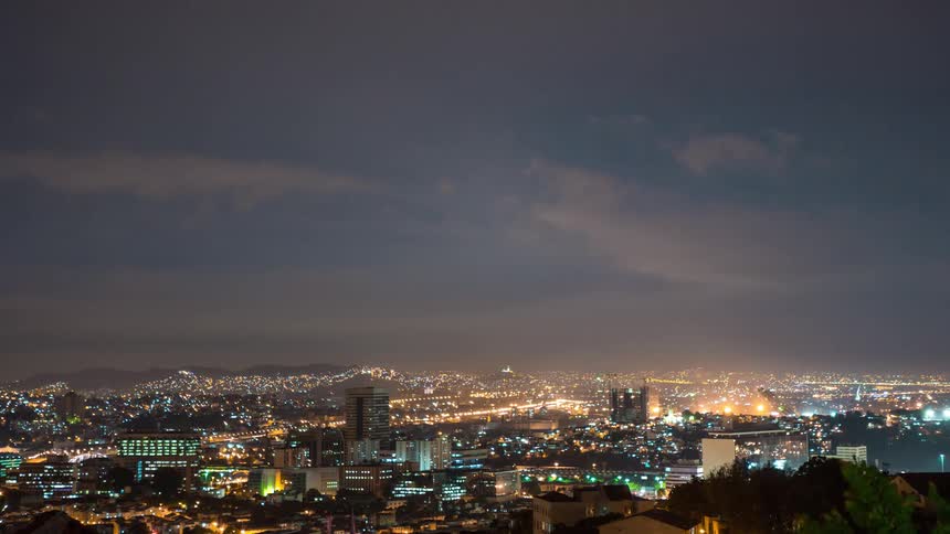 Landscape of illuminated buildings in the city of Rio, as airplanes circle above