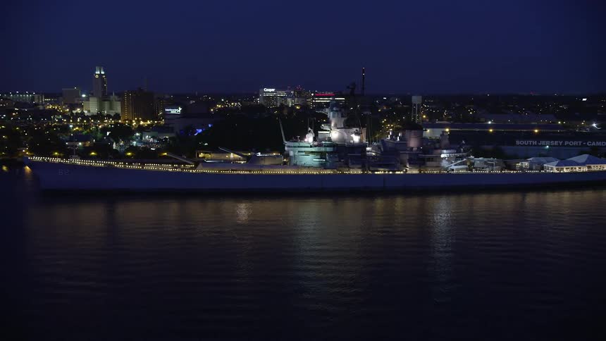 An aerial view of USS New Jersey battleship on the Delaware River at night approaching Camden New Jersey