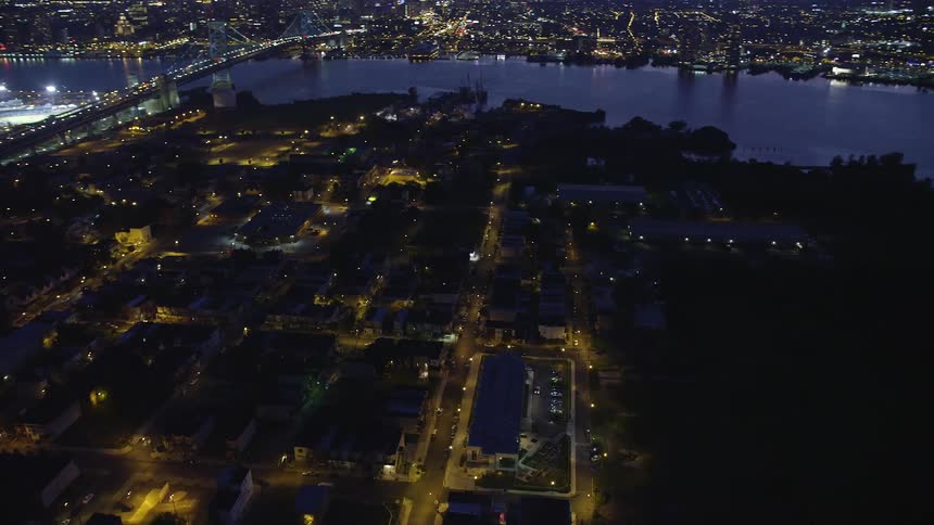 Aerial footage of nighttime fireworks display in Camden New Jersey seen orbiting the urban neighborhood with clear skies and a beautiful view of the city river
