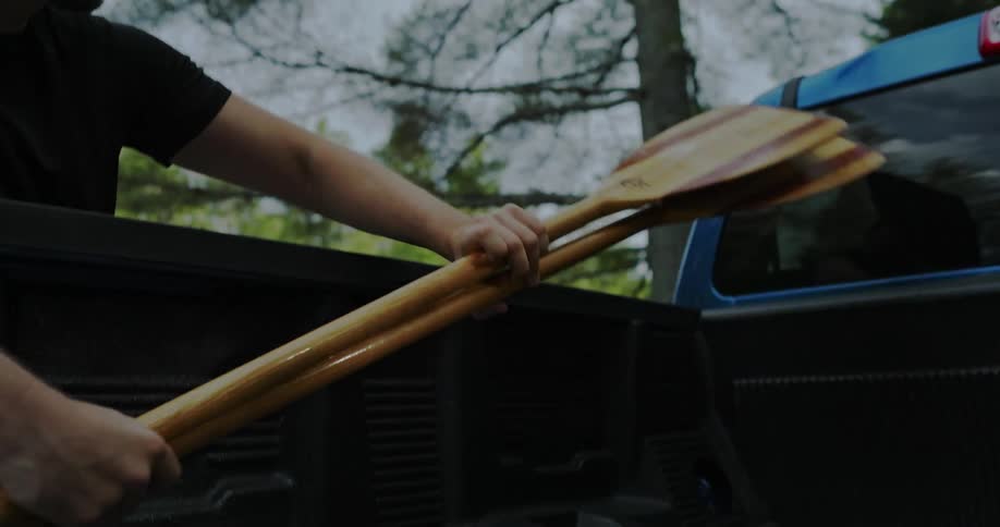 Man lifts wooden oars from truck bed