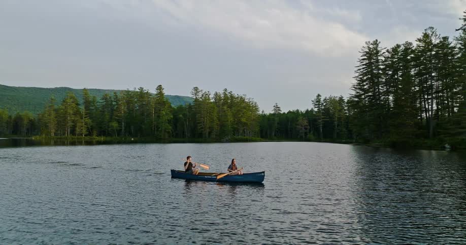 Man and woman rowing boat in lake near forest