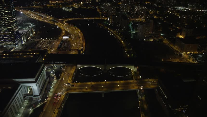 Aerial view of small bridges spanning Schuylkill River near office buildings on a clear summer night approaching the Philadelphia Museum of Art